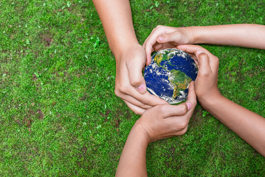 Environment conservation concept. Young children hands holding globe on green nature background for sustainable development goal.  world image by NASA