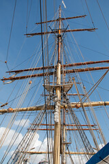 Ropes and the mast to control the sails, details of the device of the yacht, sailing ship equipment against the blue sky, vertical view