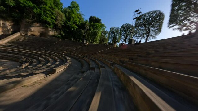 Dynamic fpv drone shot cruising around ancient amphitheater sunny day 