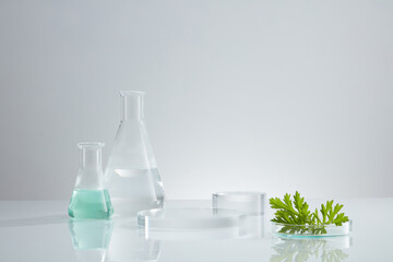 Front view of transparent podium with laboratory equipment and mugwort in white background science content