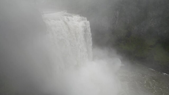 Torrent of water crashes over Snoqualmie Falls as mist rises from the base