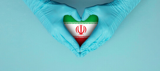 Doctors hands wearing blue surgical gloves making hear shape symbol with iran flag