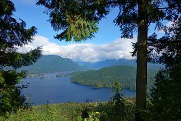 Fototapeta na wymiar Panoramic view of Burrard Inlet, BC, with mountain and cloud backdrop, as viewed from Burnaby Mountain park in late summer.