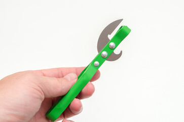 green metal bottle opener in a male hand on a white background