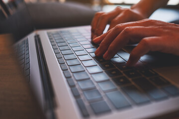 Closeup image of a woman working and typing on laptop computer keyboard in office