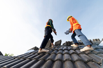 Builders in work clothes install new roofing tools, roofing tools, electric drill and use them on new wooden roofs with metal sheets