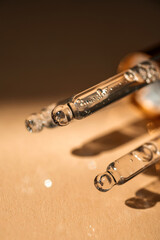 Three pipettes of cosmetic gel on a beige background.