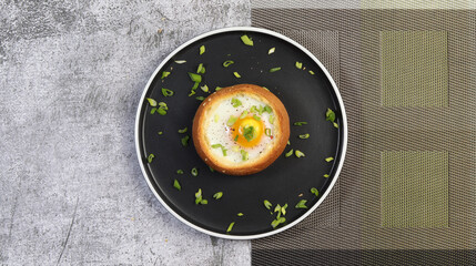 Baked Egg in Bread Bowl on a round plate on a dark grey background. Bun with egg. Top view, flat lay.