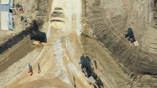 Above top view, overhead on blade leveling machine, grader, until is leveling layer of fraction, small crushed stone, road under construction. Roller with spikes is working, compacting sand.