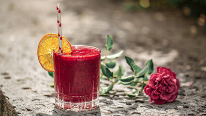 Glass of fresh berry smoothie with orange slice and straw