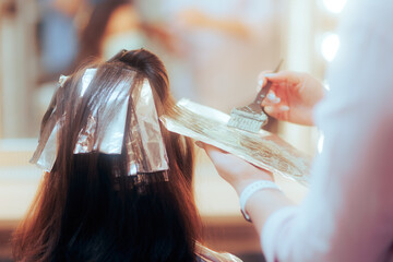 Professional Hair Colorist Dying a Piece of Hair in a Salon. Hairdresser using tin foil for...