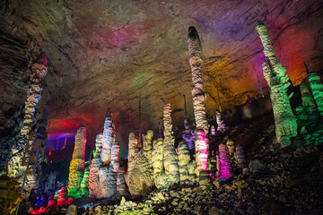 Stalactites in Huanglong cave, horizontal background image with copy space for text, colorful lighting, tall ceiling of the cave