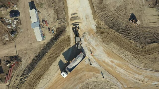 Above top view, overhead on tipper truck as lifting his trailer to unload cargo, fraction, small crushed stone for new circular road, roundabout under construction.
