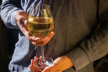 Man holding a glass of white wine with both hands