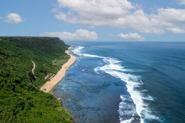 Fototapeta premium aerial of Nyang Nyang beach in Uluwatu Bali Indonesia on a sunny day as blue ocean waves crash on the sandy shore of a white sand beach