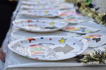 Graduation party plates set up at a decorated table for an outdoor graduation party