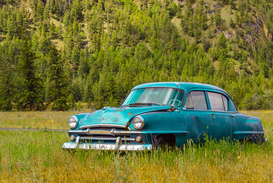 Abandoned rustic car on the hill in summer park