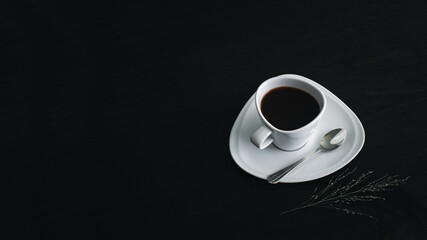 Cup of black coffee on black wood table dark background. White porcelain cup on saucer. Copy space for text.  Top above view.
