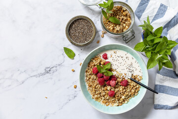 Breakfast, sweet dessert. Diet nutrition concept. Homemade granola with yogurt, chia seeds and raspberry on a marble tabletop. View from above. Copy space.