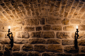 ancient stone wall with candles architecture background, religion, light and shadow concepts