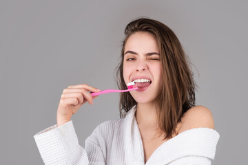 Beauty portrait of a happy beautiful woman brushing her teeth with a toothbrush isolated...
