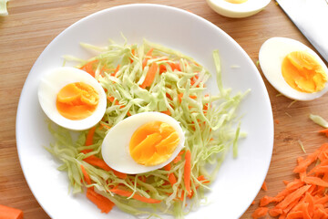 Boiled egg salad with cabbage and carrot. Coleslaw with boiled on a white plate.