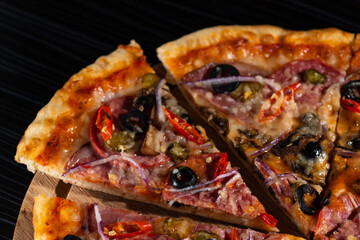 bright pizza on a dark table. pizza with olives and red pepper