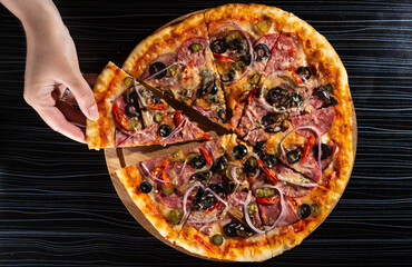 bright pizza on a dark table. pizza with olives and red pepper