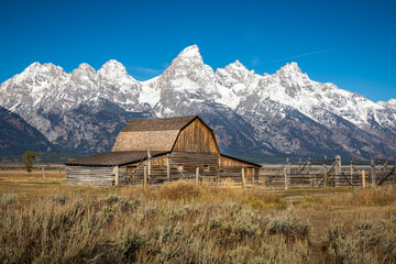 Iconic wooden barn in field with background of Grand Teton.