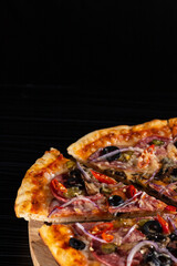 bright pizza on a dark table. pizza with olives and red pepper