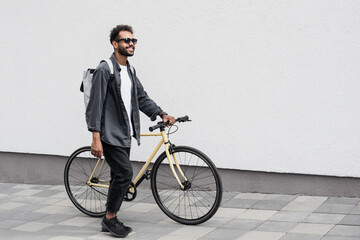 Young handsome man with bike over white wall background in a city, Smiling student man with bicycle...