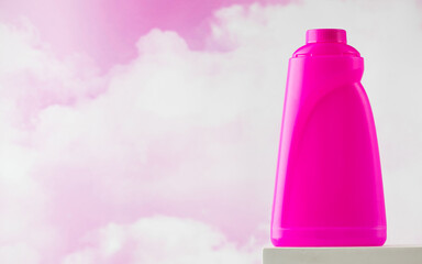 Pink container with bleach or washing gel against the background of pink clouds.