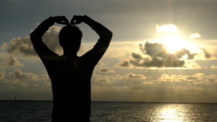 Blurred silhouette young man looking at sea while sunset.