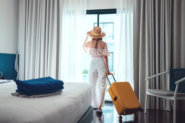Tourist woman with luggage in hotel after check-in. Conceptual of travel and vacation.