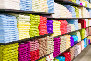 Multicolor towels on shelf in market, sale cotton towels, stack colored cotton towels, a shelf in the home row of the market, close-up selective focus