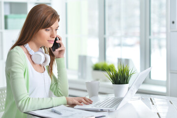 Young businesswoman talking on phone while sitting in the office