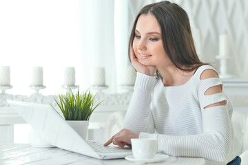 Portrait of beautiful young woman using modern laptop at table