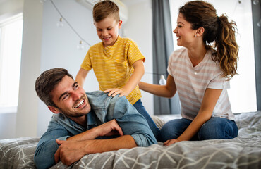 Fototapeta premium Happy family. Beautiful young parents having fun, playing with their son at home.