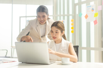 Two young adult business asian woman using laptop for working at office table