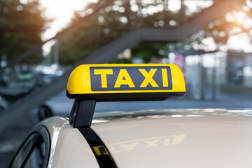 Close-up detail yellow taxi symbol on cars roof stand waiting at parking of airport terminal or...