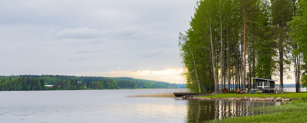Typical Finnish little wooden house along lake at the countryshide