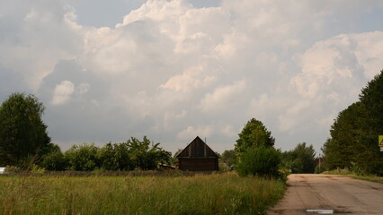 Obraz premium Beautiful rustic summer landscape with road. Old wooden log houses. Vologda region