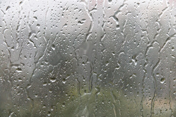 Raindrops run down the window pane. Rainy weather. Soft selective focus.
