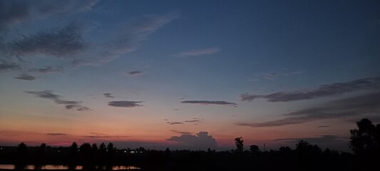 sunset in the village, blue sky, trees, clouds in the sky 