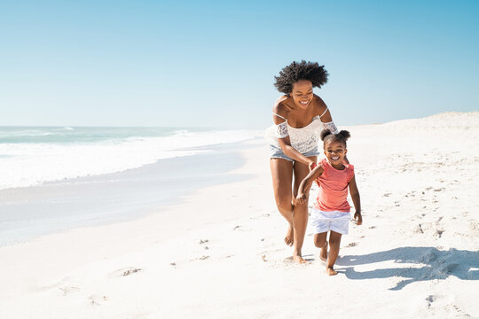 African mother running after her daughter on the beach