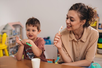 teacher in kindergarden educating kids how to brush teeth