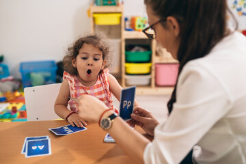 psychologist having speech support session with young girl in kindergarden