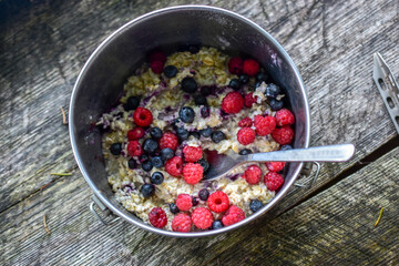 Raspberry and blueberries with oatmeal on a wooden table, top view