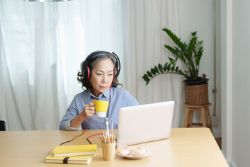 relax time, Portrait of an elderly woman listening to music happily to relax between computer sessions