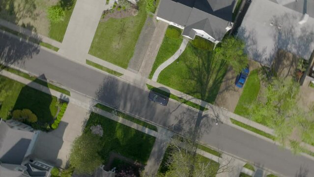 Aerial straight down over suburban houses and street with a bike rider on the street as camera spins.